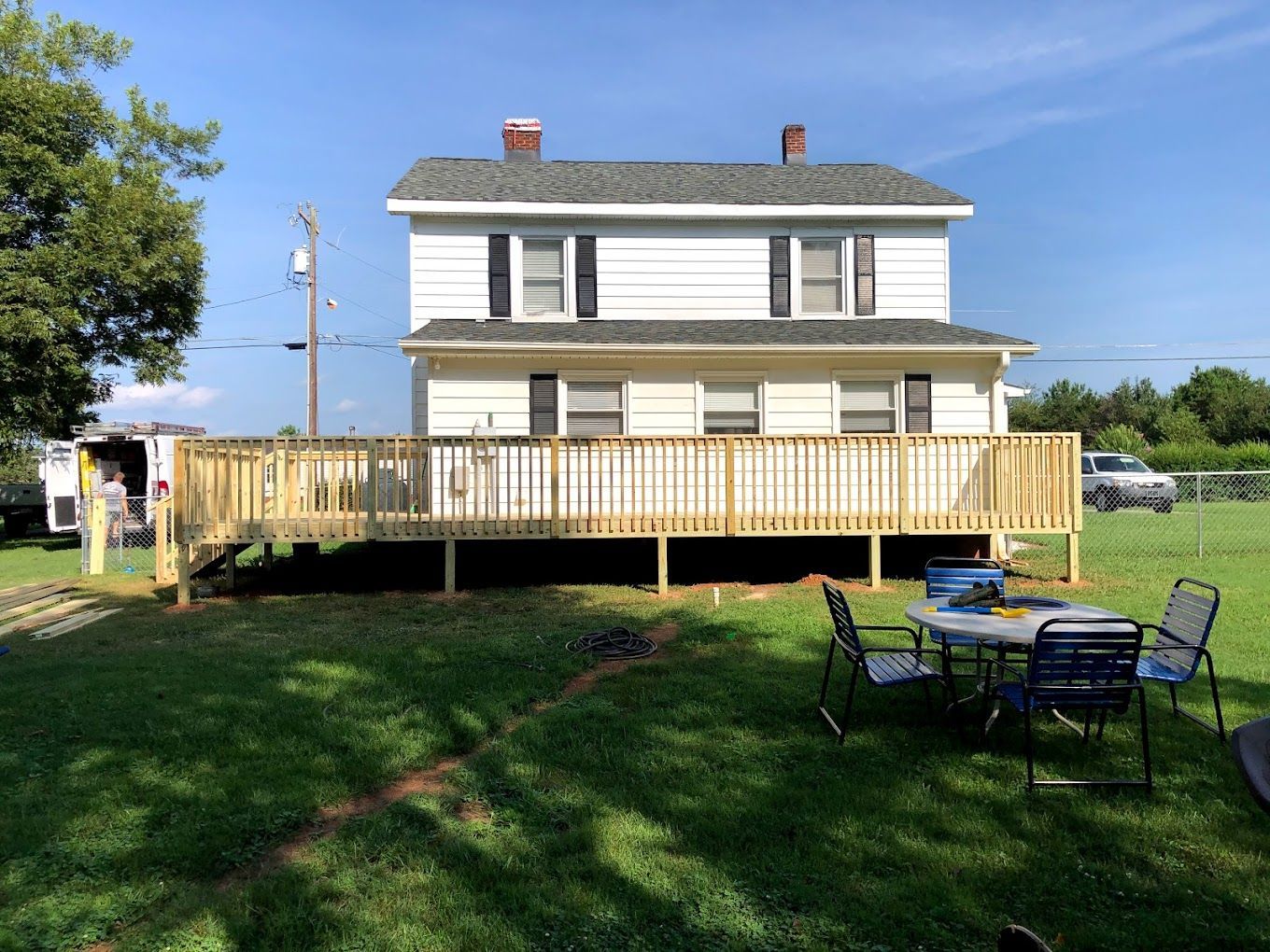A house with a wooden deck and a table and chairs in front of it.