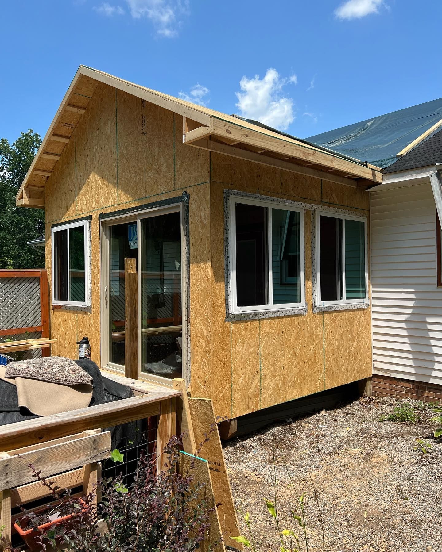 A small house with a lot of windows is being built in the backyard.