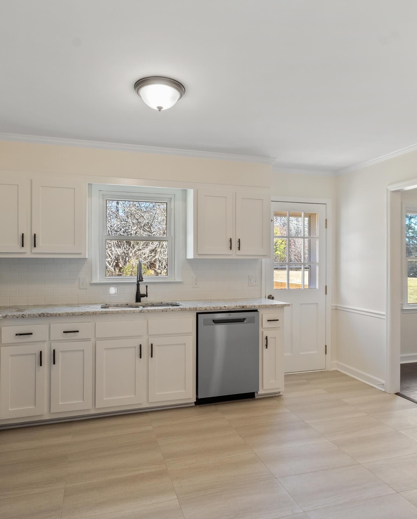 An empty kitchen with white cabinets and a stainless steel dishwasher.