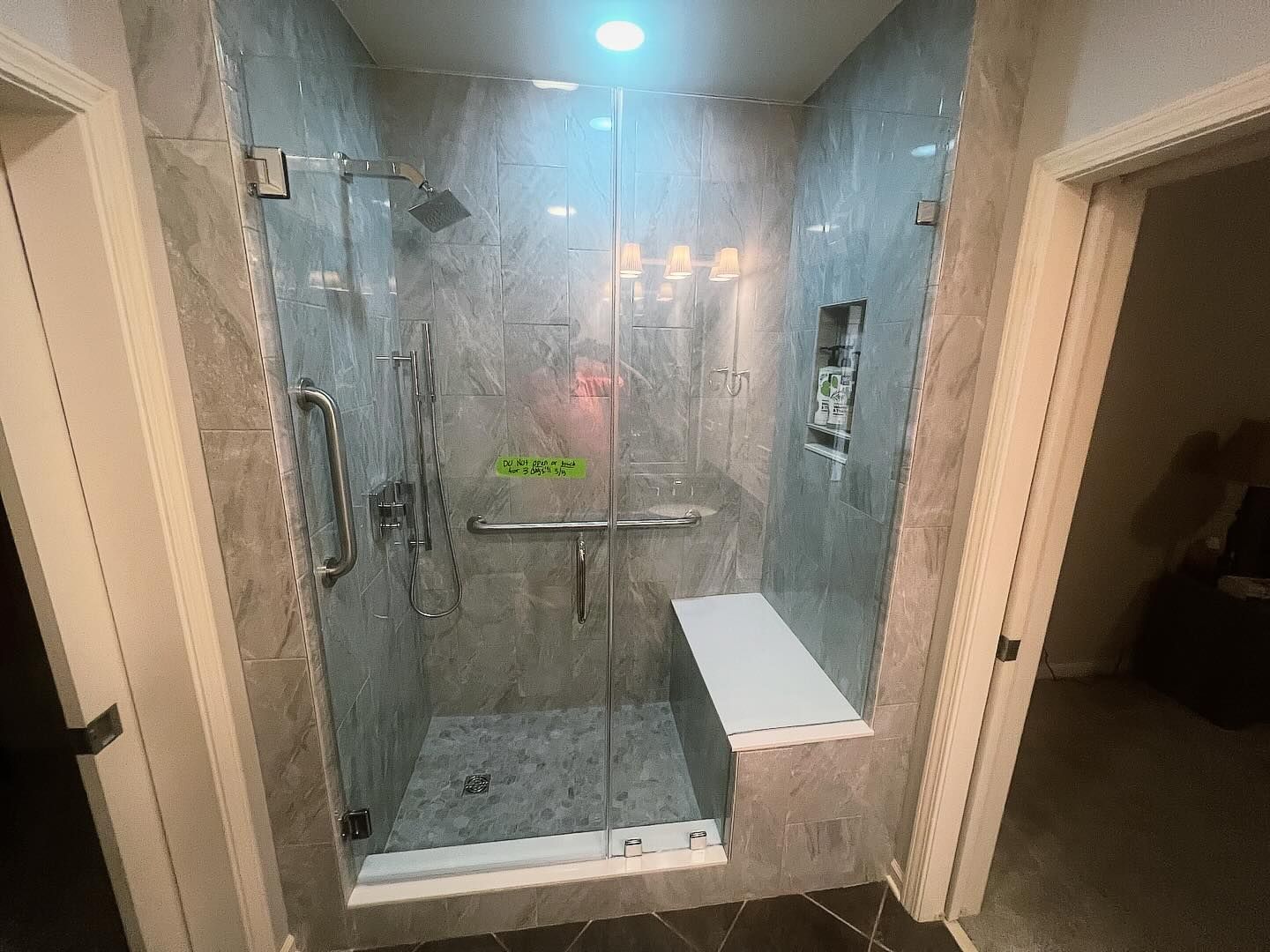 A bathroom with a walk in shower and a bench.