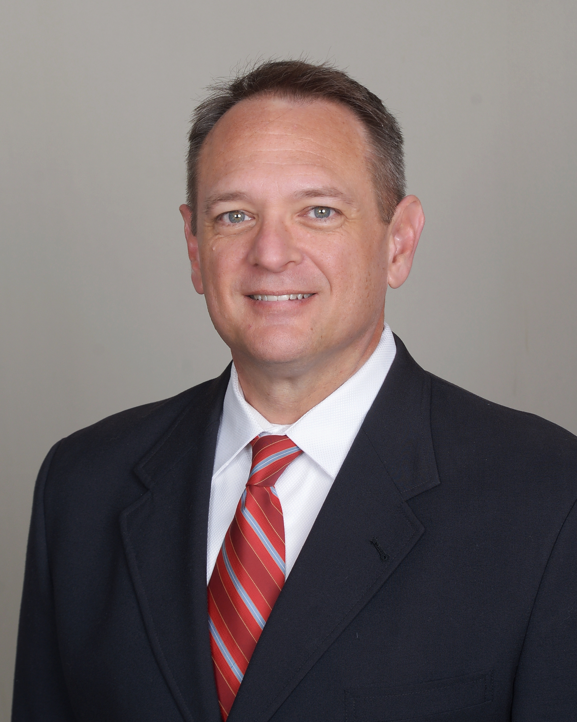 A man in a suit and tie is smiling for the camera