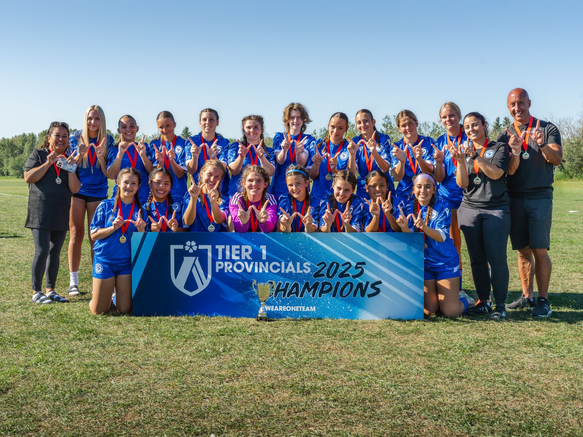 A soccer team in blue jerseys stands behind a