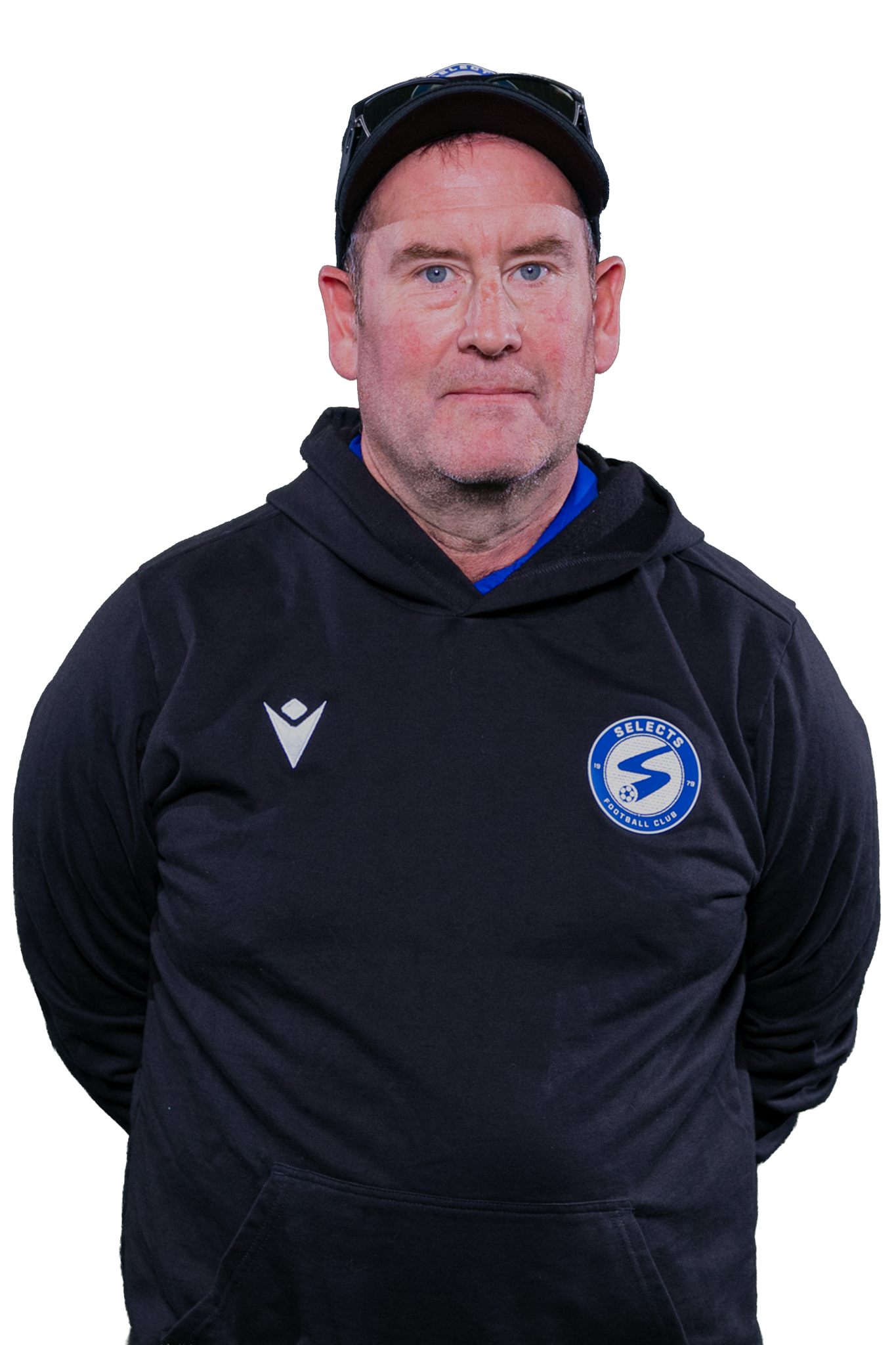 Person in a black hoodie and cap, standing against a white background, looking at the camera.