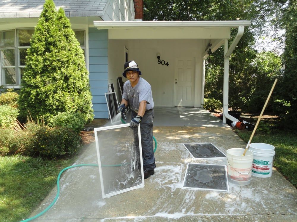 A man is cleaning a screen door with a hose