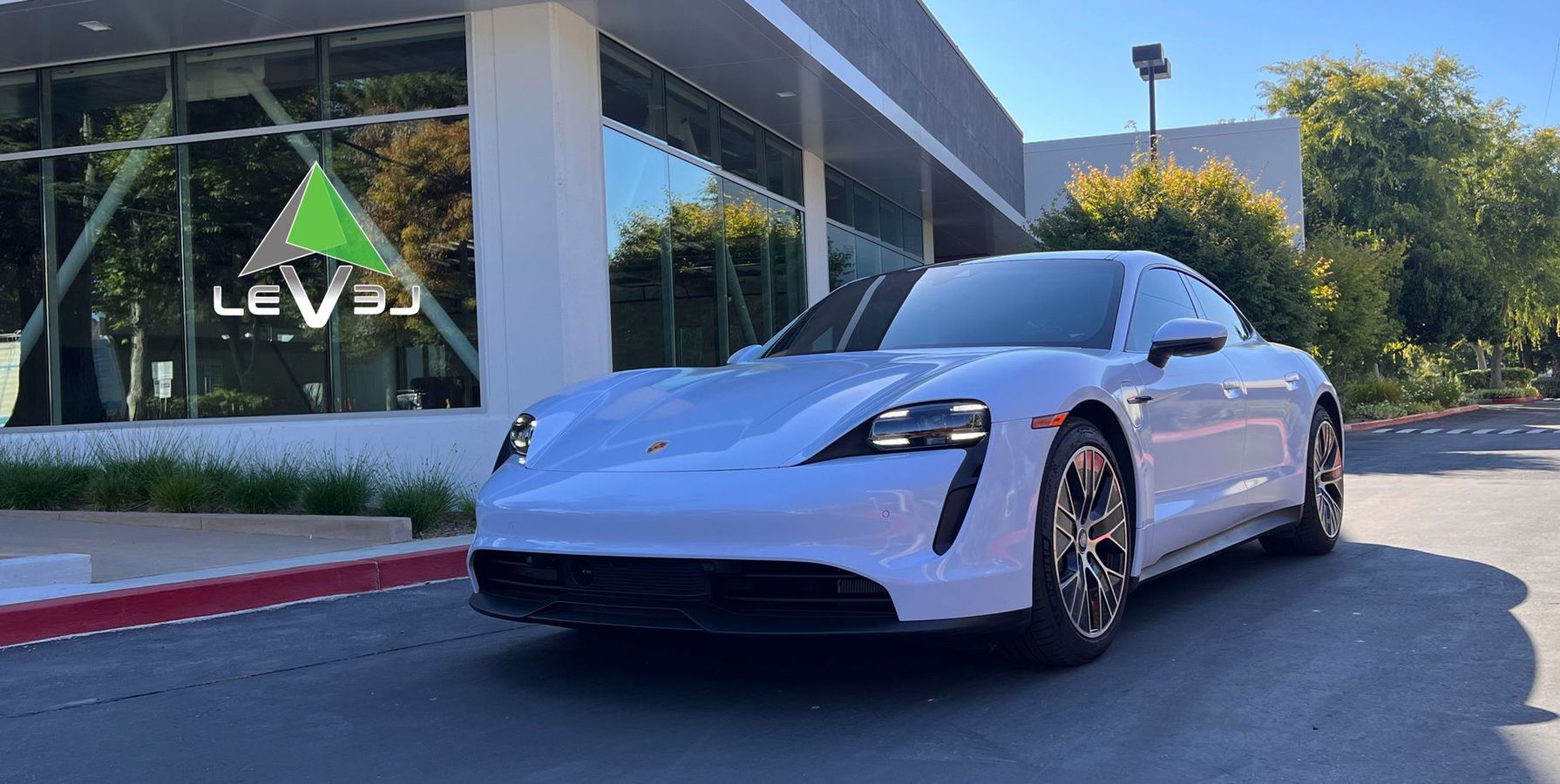 White sporty sedan parked outside a modern building with a Levi’s sign.