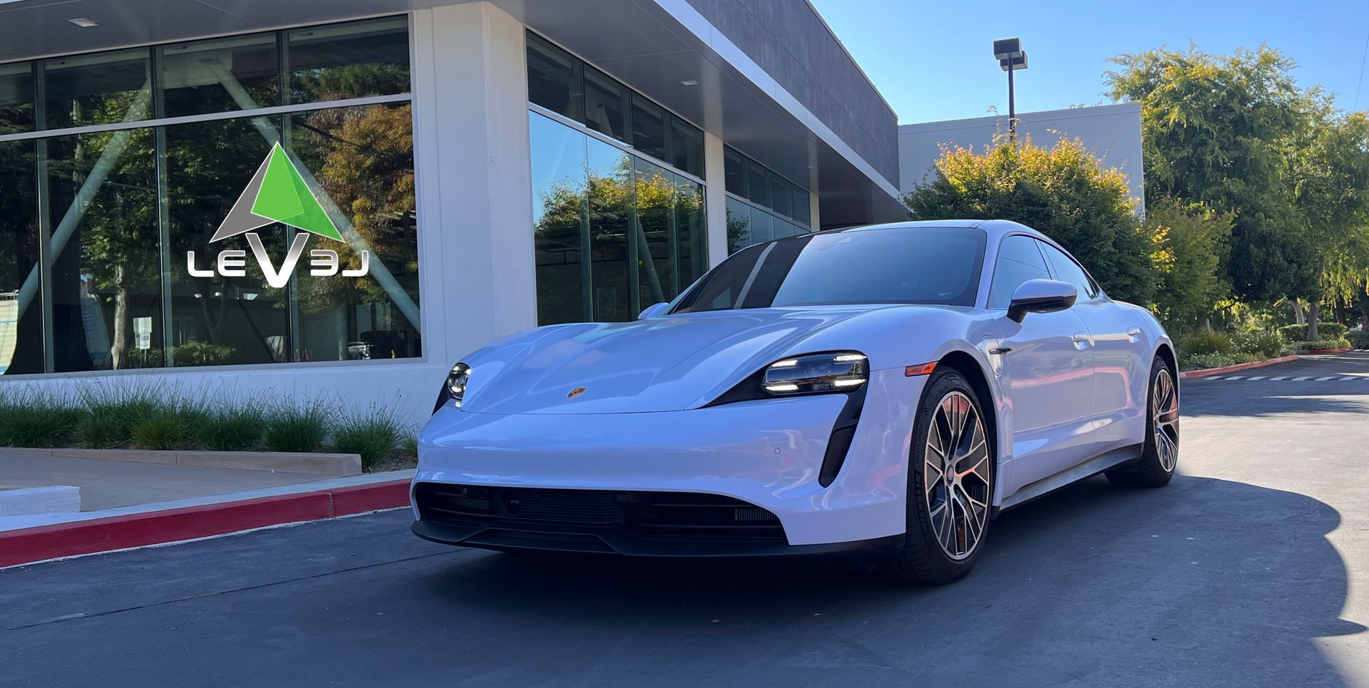White sporty sedan parked outside a modern building with a Levi’s sign.