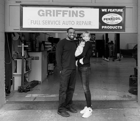 Man holding a child in front of Griffins Full Service Auto Repair garage sign