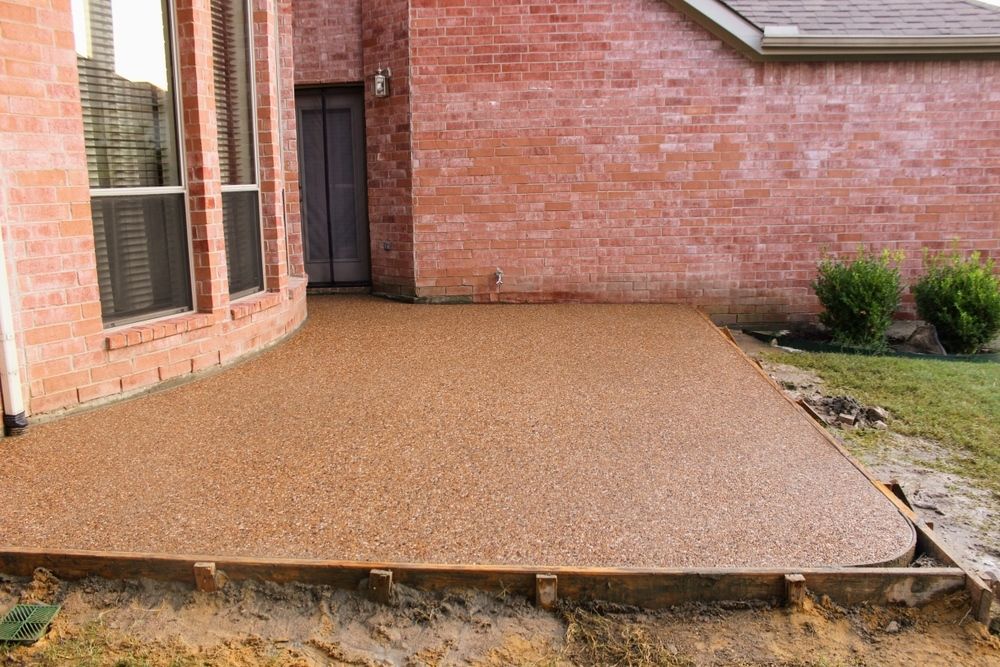 Brown Speckled Concrete Patio Outside a Brick House — Grafton Concreting & Bobcat Services In South Grafton, NSW