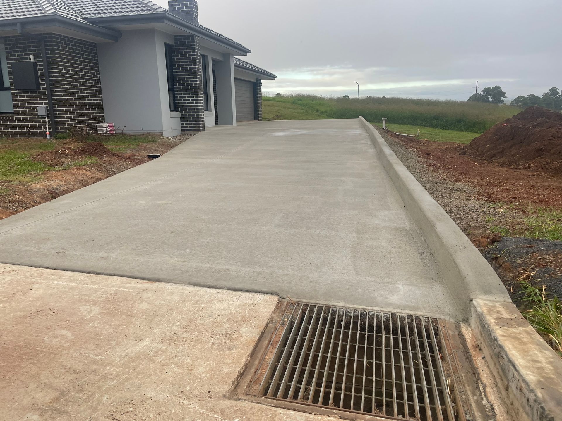 A Concrete Driveway is Being Built in Front of a House — Grafton Concreting & Bobcat Services In South Grafton, NSW