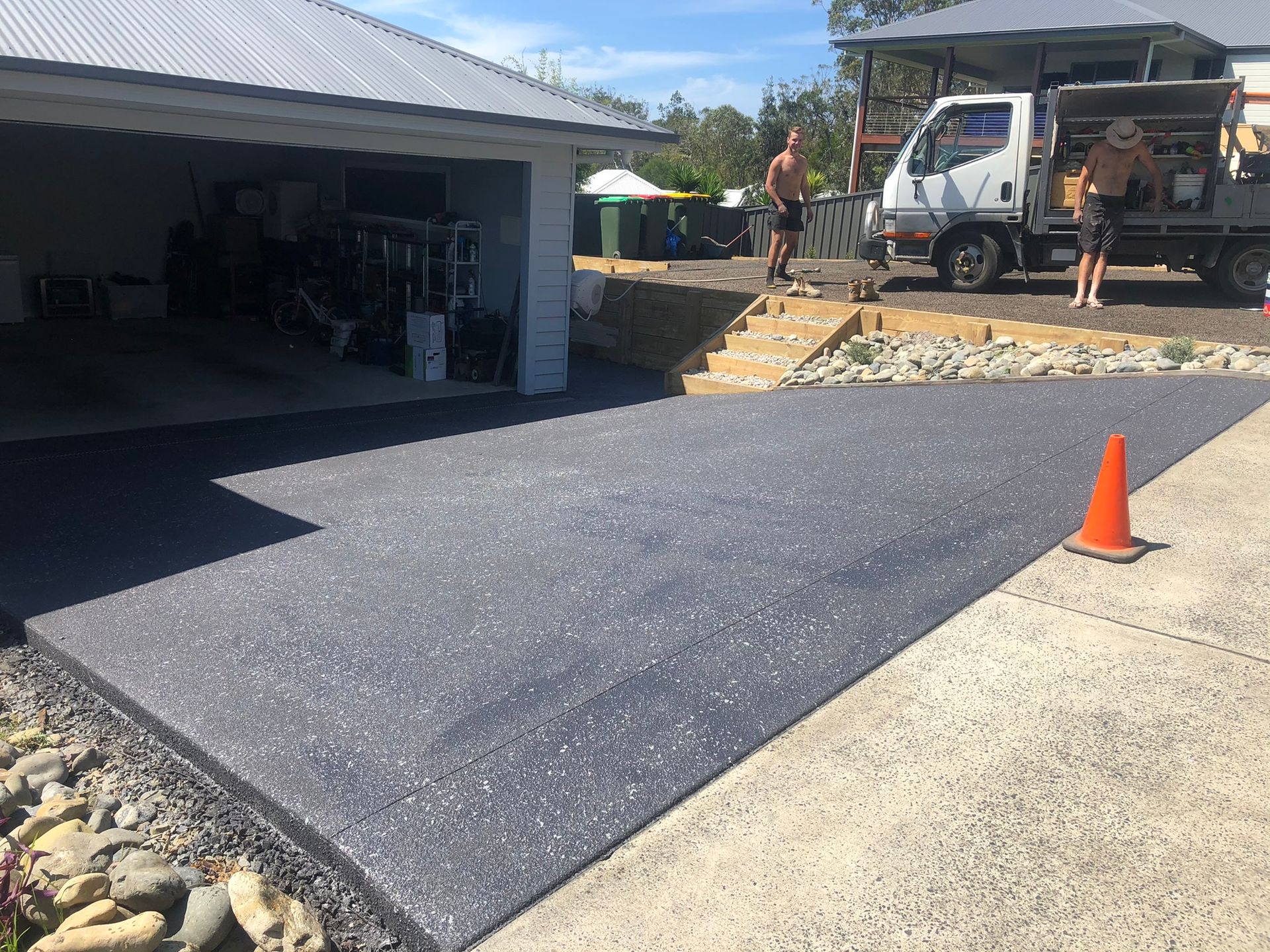 A Black Patio With a Fence and Workers in the Background — Grafton Concreting & Bobcat Services In South Grafton, NSW