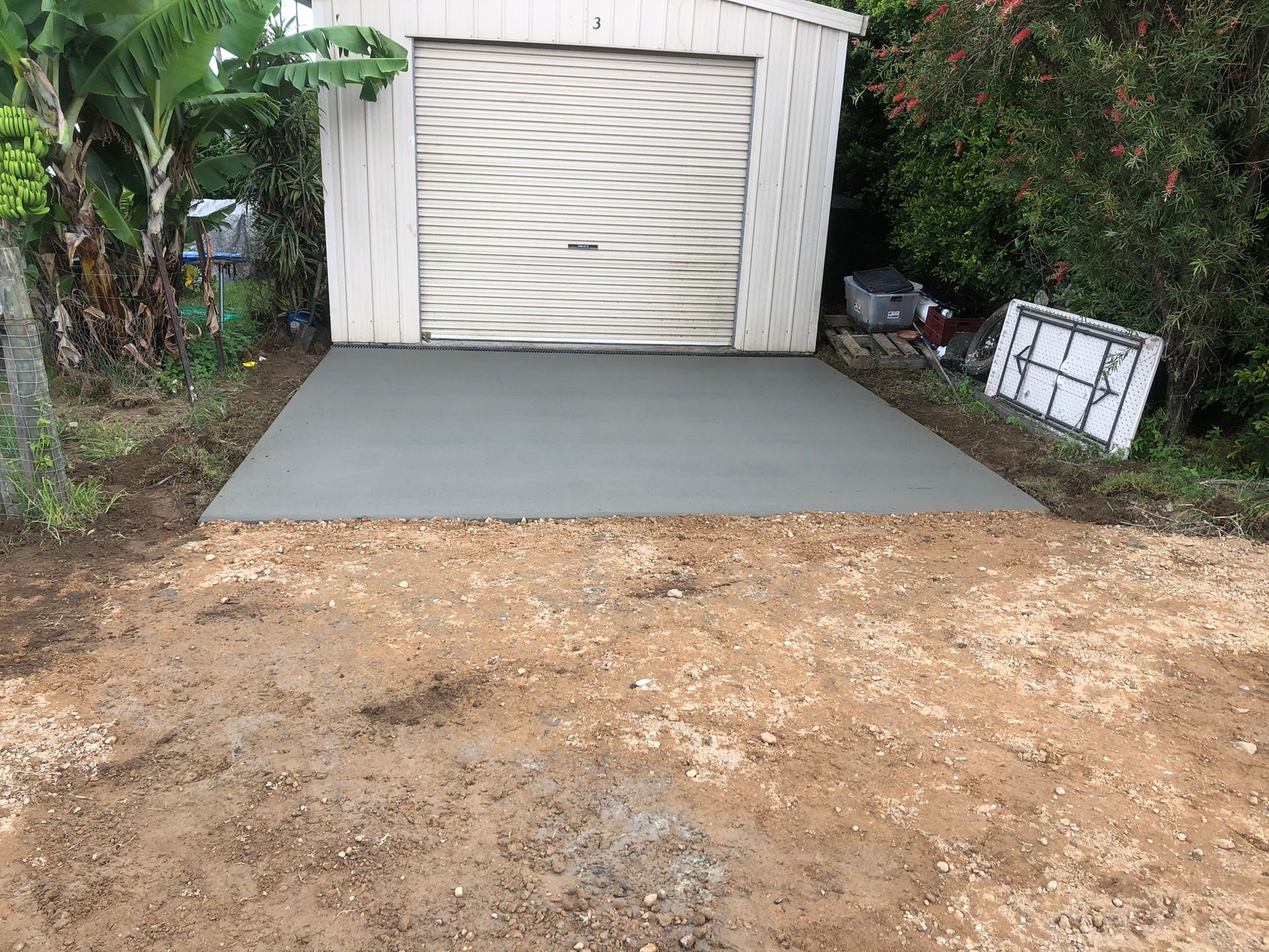 A White Garage With a Concrete Driveway in Front of It — Grafton Concreting & Bobcat Services In South Grafton, NSW
