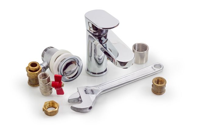 Chrome faucet parts and wrench on white background