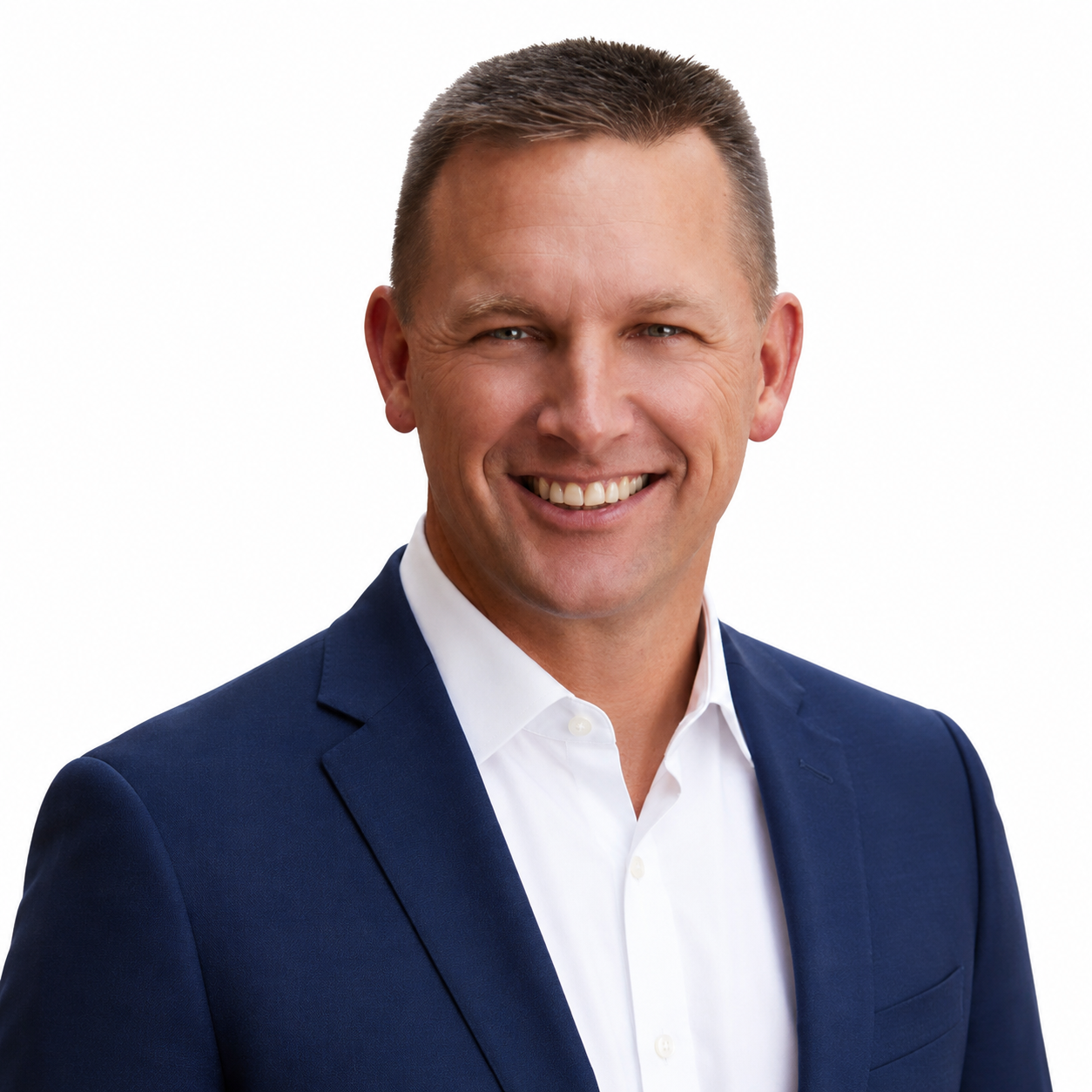 Man in a blue blazer and light blue shirt smiles, headshot against a white background.