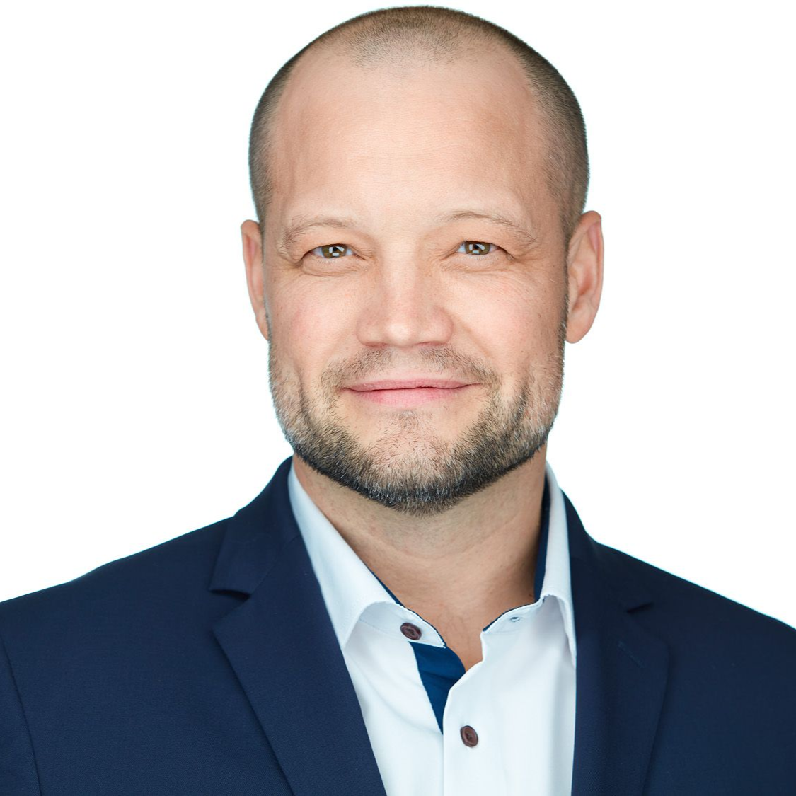 Man in blue blazer smiles, headshot.