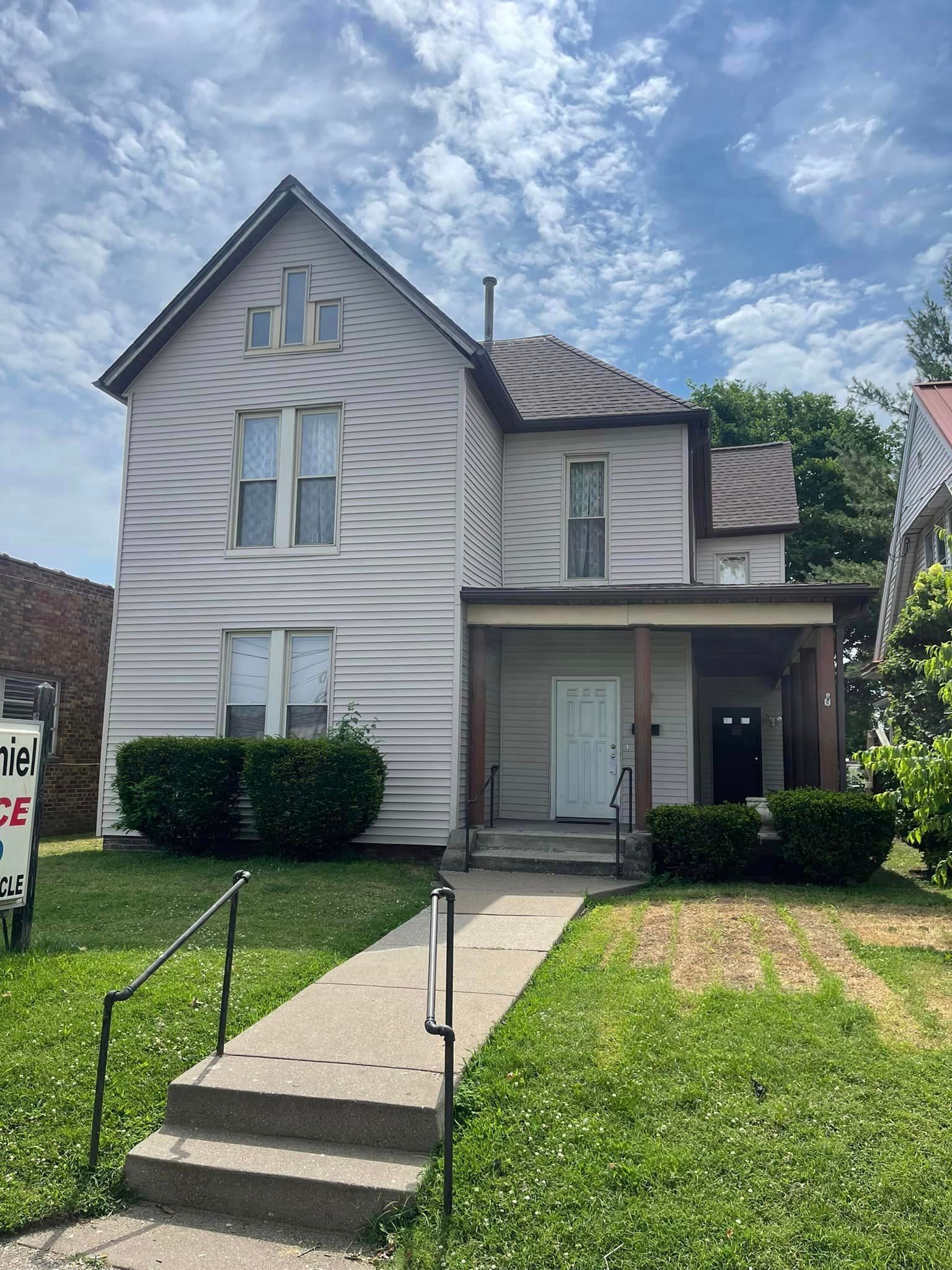 A large white house with a porch and stairs is for sale.