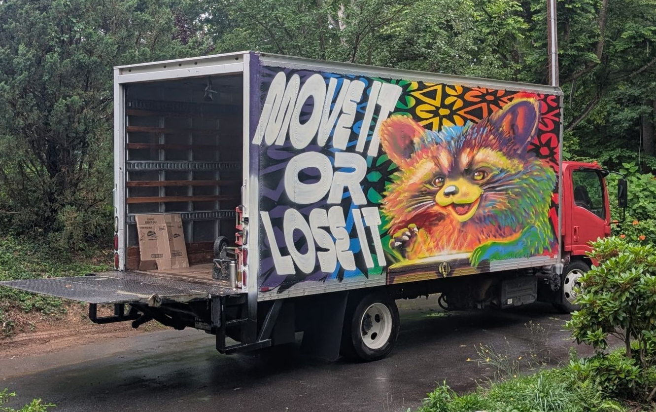 The Move It or Lose It moving truck surrounded by the greenery of Western North Carolina. 