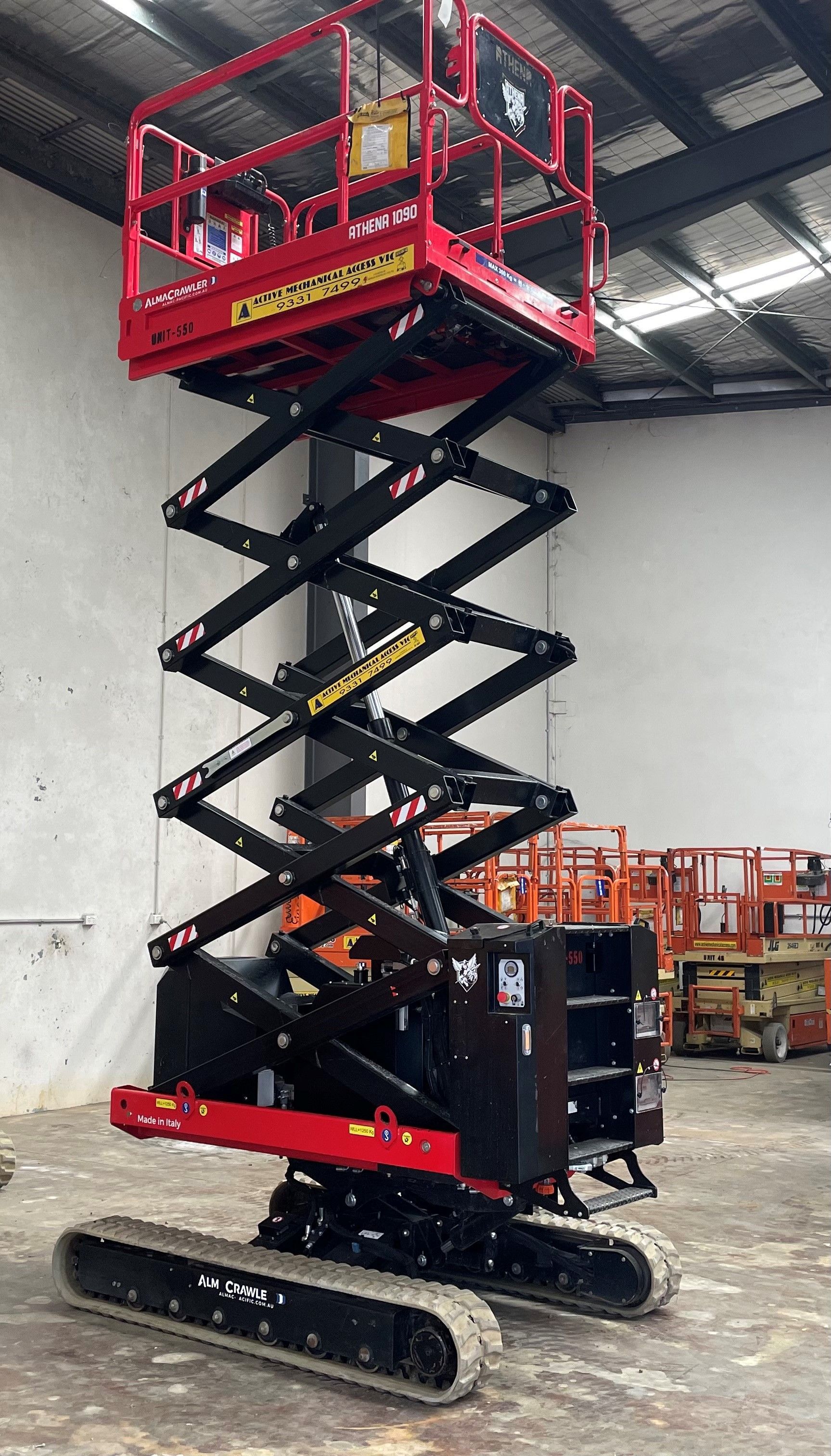 Two orange scissor lifts are parked next to each other