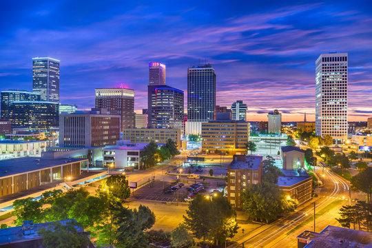 Downtown skyline at dusk with illuminated high-rises, colorful clouds, and streetlights below