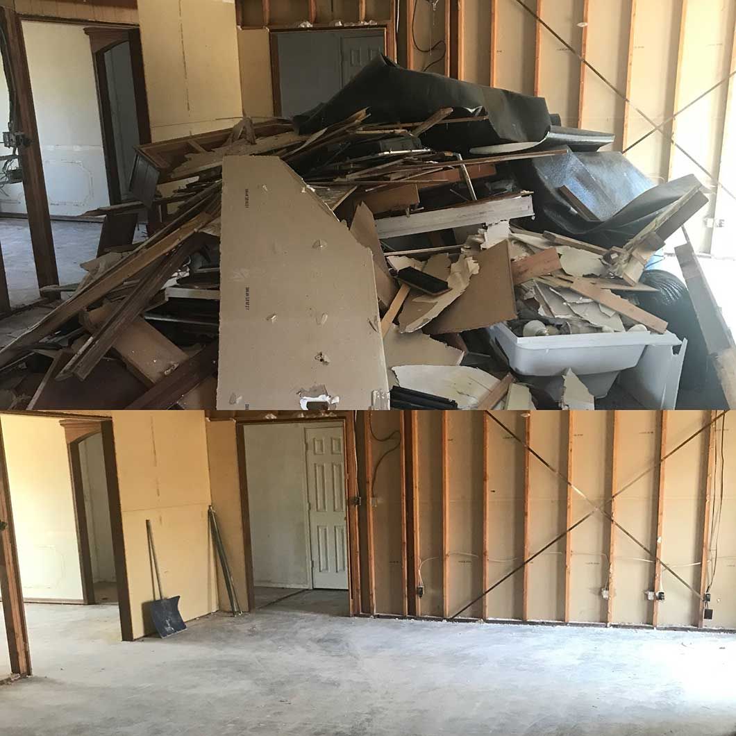 Interior room with a pile of debris in one corner and exposed wall studs in the cleaned space below.