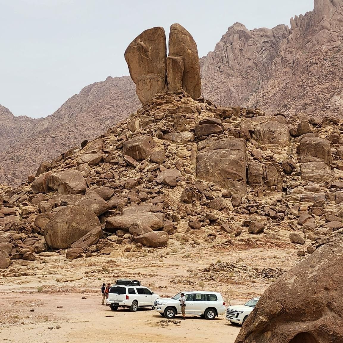 A group of cars are parked in front of the Split Rock of Moses