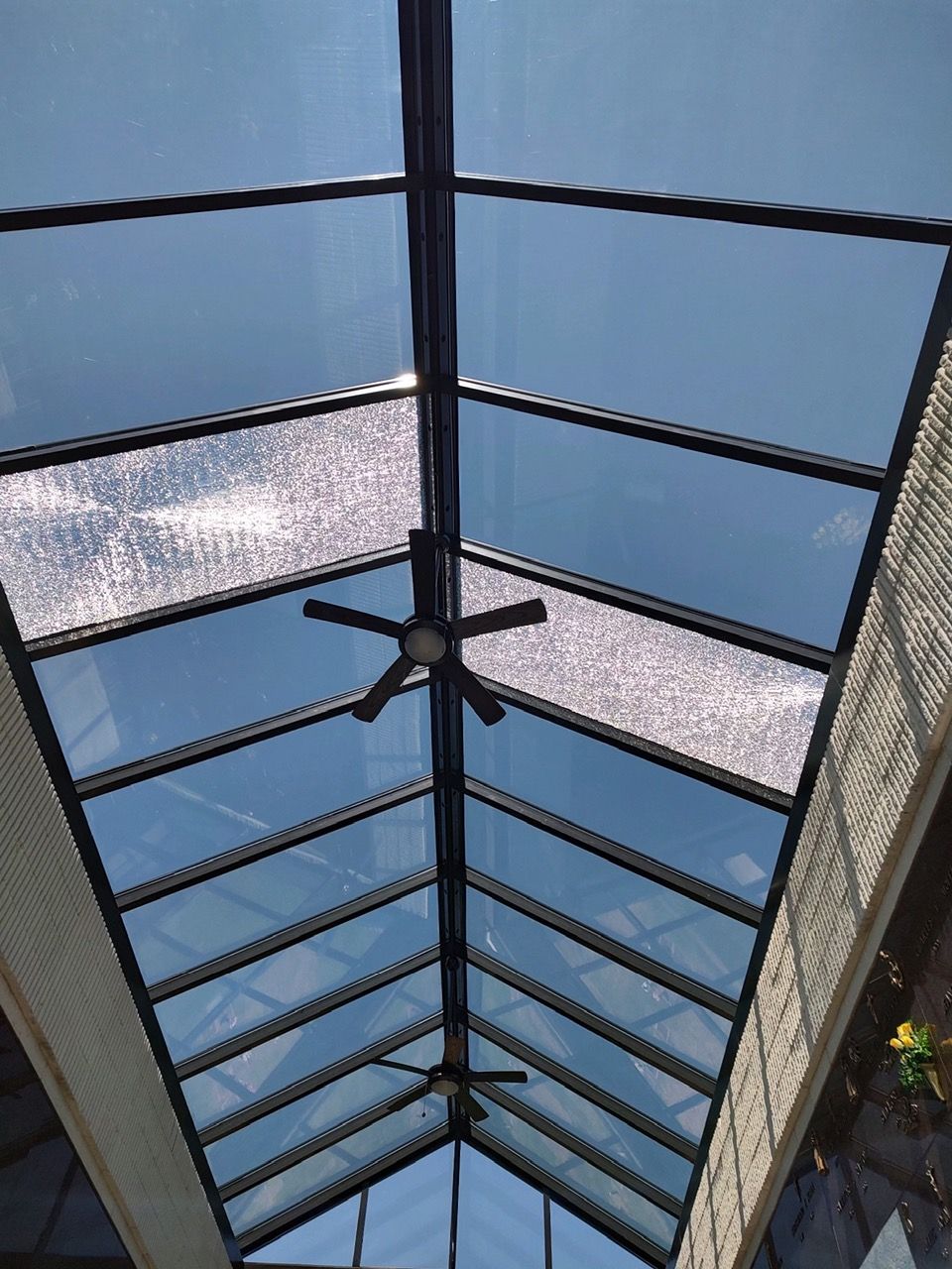 Skylight with black framing, two ceiling fans, and blue sky visible.