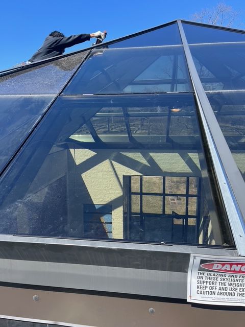 Person cleaning a glass pyramid roof. A