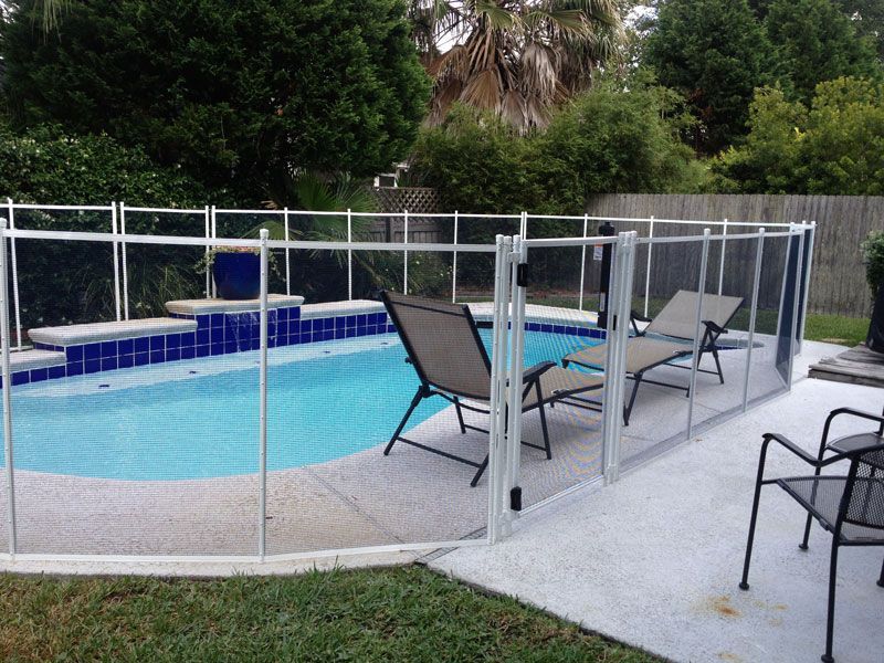 A fence surrounds a large swimming pool in a backyard