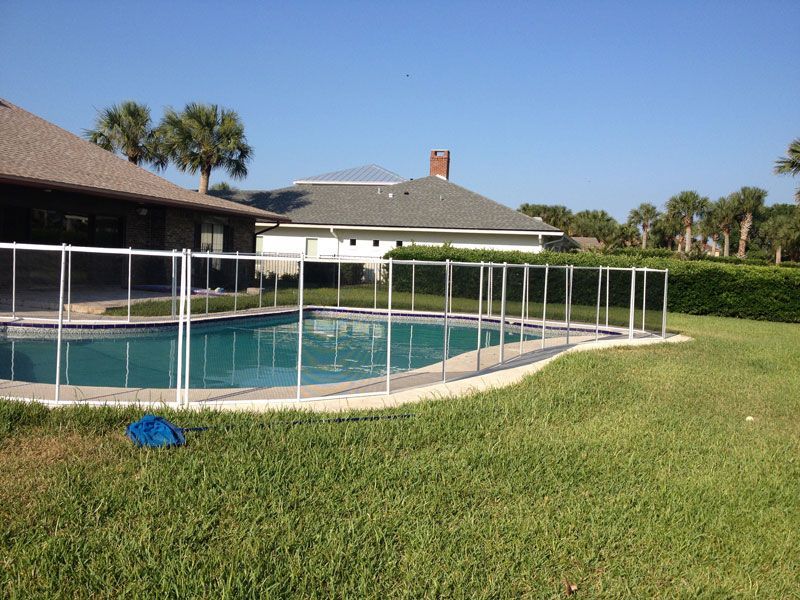 A swimming pool with a fence around it and a house in the background