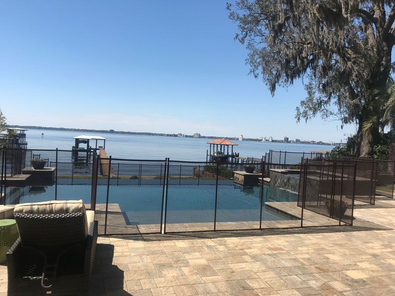 A large swimming pool surrounded by a fence overlooking a body of water.