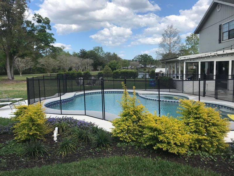 A large swimming pool with a fence around it and a house in the background.