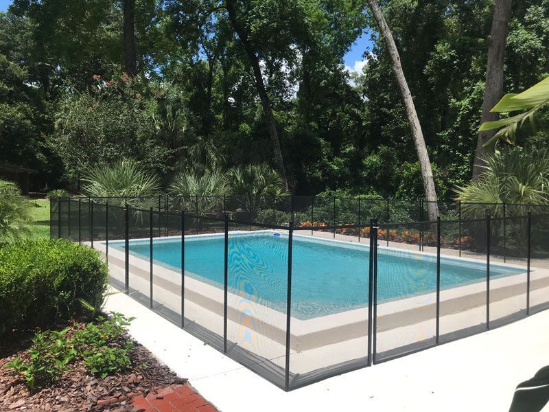 A swimming pool with a fence around it and trees in the background.