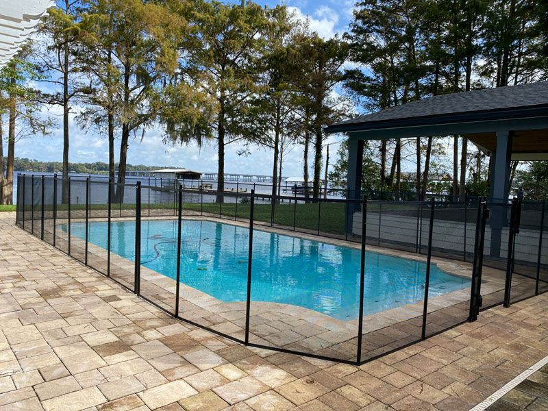 A swimming pool with a fence around it and a gazebo in the background.
