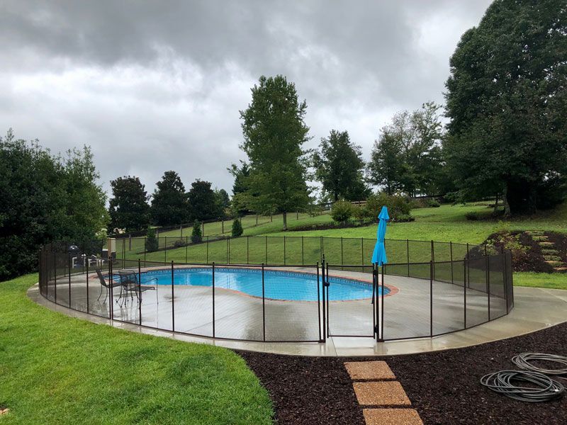 A swimming pool with a fence around it and a blue umbrella.