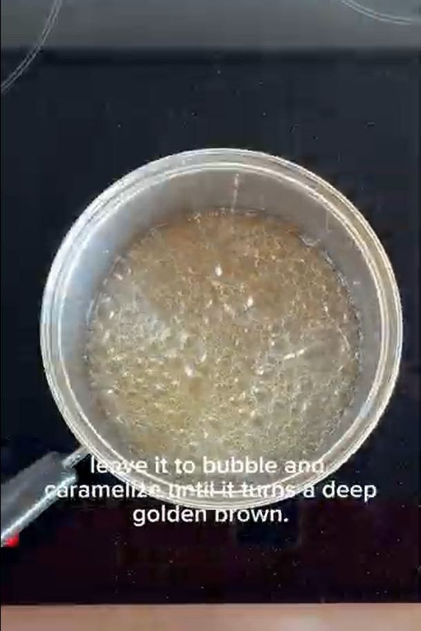 A saucepan on a stovetop with boiling sugar syrup, with text instructions to caramelize until deep golden brown.
