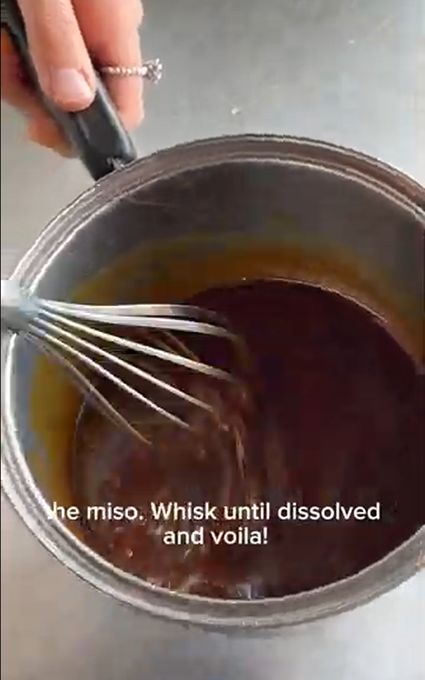A hand uses a whisk to stir miso into a dark brown liquid in a metal saucepan, with text overlays about dissolving miso.