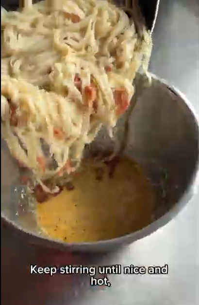 Creamy pasta being poured into a metal bowl containing a golden sauce, with the text