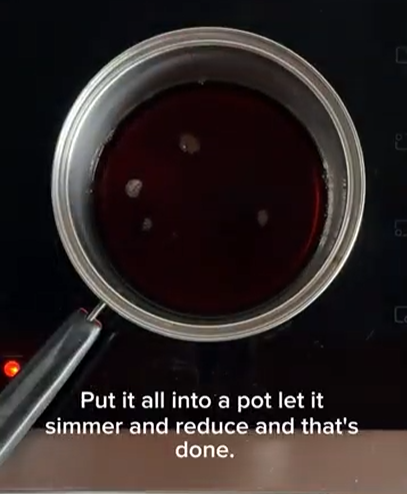 A small pot containing dark red liquid simmering on a stovetop, with text reading, 