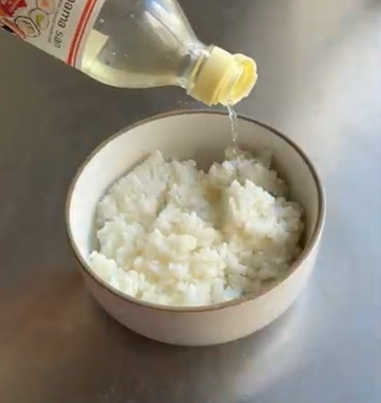 Bottle pouring liquid into a bowl of rice