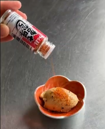 Oil being poured into a bowl of chopped tomatoes, onions, and spices on a metal countertop