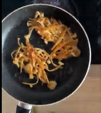 Pan with a small pile of cooked shredded vegetables on a stovetop