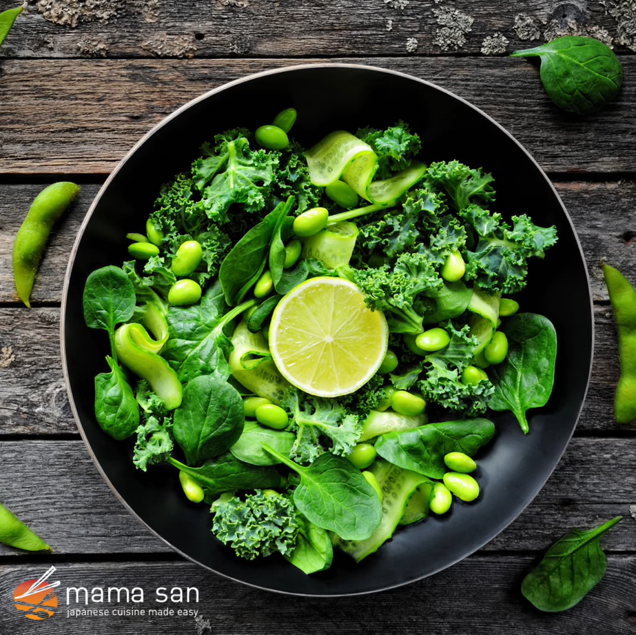Green salad with kale, spinach, edamame, cucumber, and lime in a black bowl on wood.