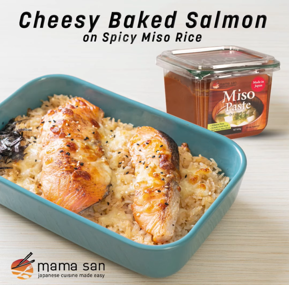 Cheesy baked salmon on spicy miso rice in a blue dish, with a miso paste container on the side.