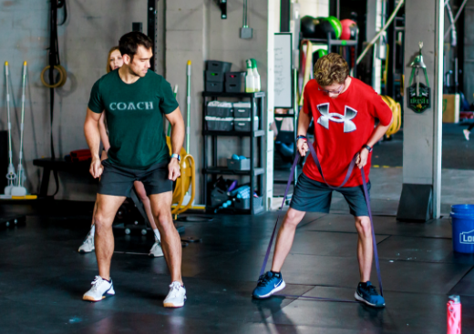Two men in workout clothes doing a side lunge exercise in a gym in Winter Park, FL