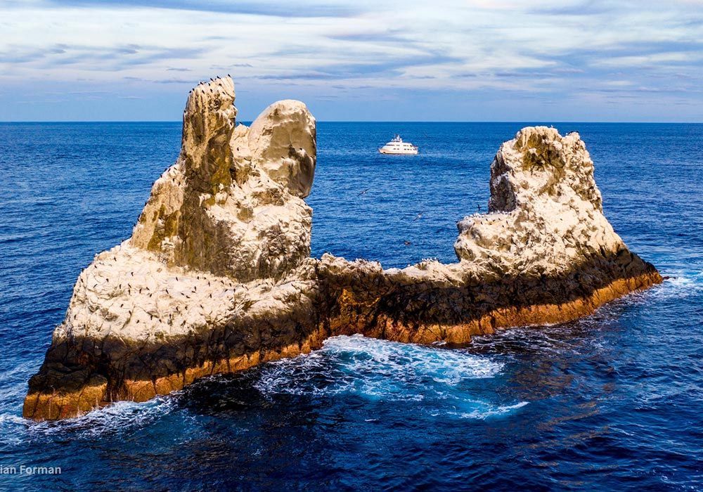 A large rock formation in the middle of the ocean.