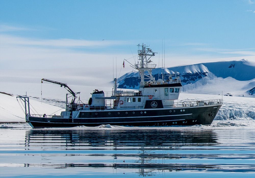 Fishing boat on calm water with snowy mountains in the background