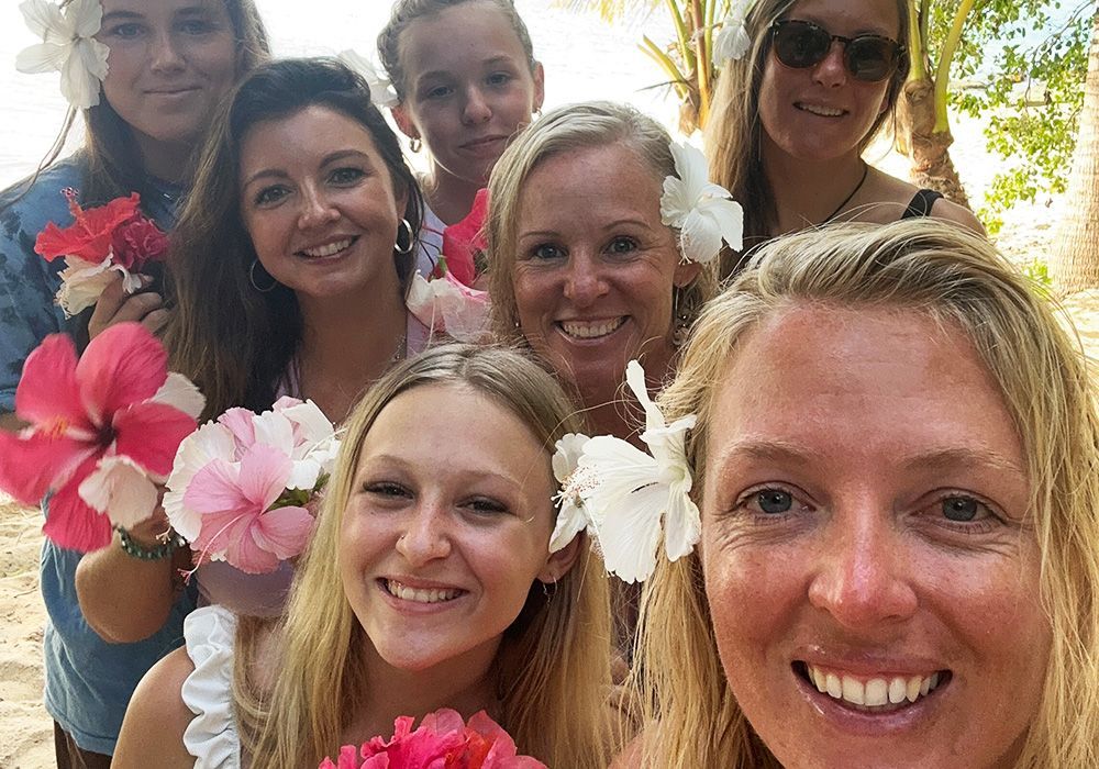 Smiling group selfie with pink and white flowers outdoors