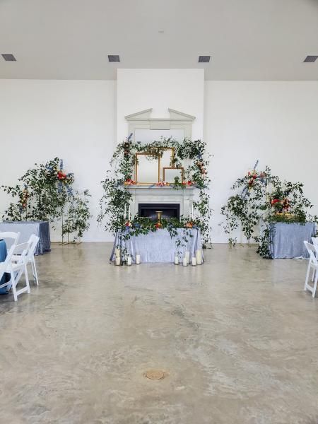 Floral-decorated memorial altar with white draping and arrangements in a bright indoor hall