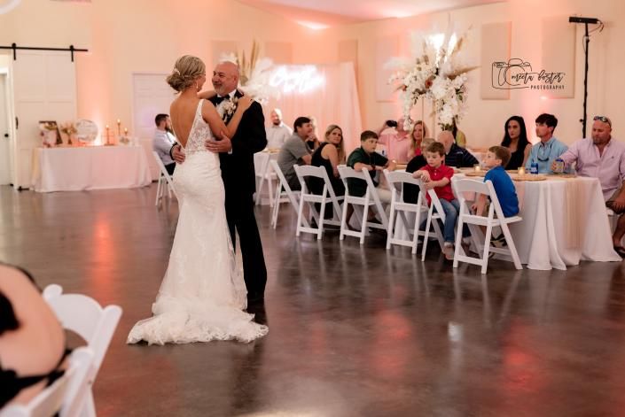Bride and groom dancing at a wedding reception with seated guests watching