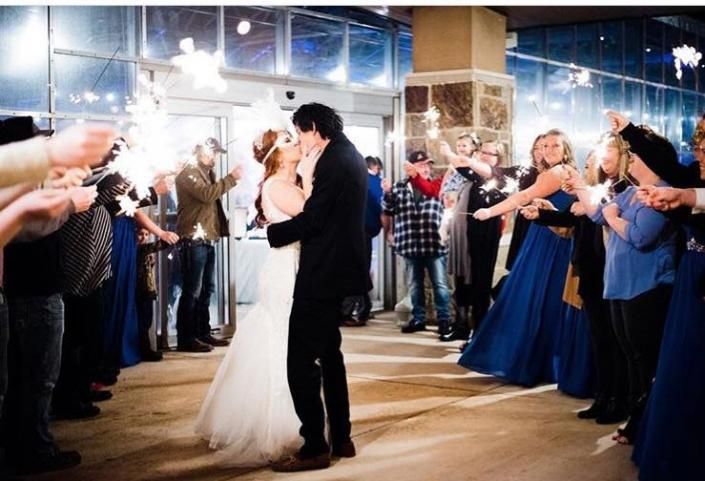 Bride and groom kissing as wedding guests cheer and clap indoors