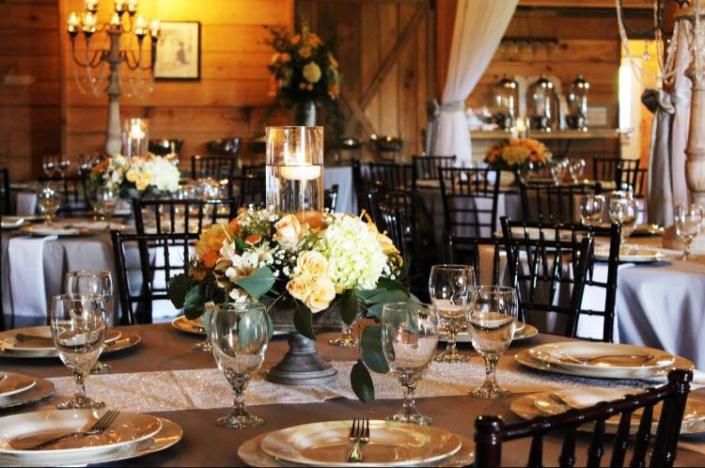 Elegant banquet table with white floral centerpiece, glassware, and candles in a warmly lit dining room
